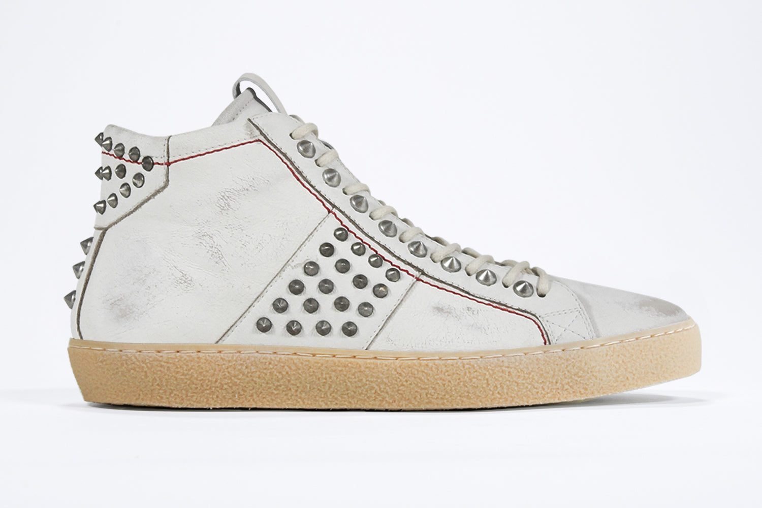Side profile of mid top aged white sneaker. Full leather upper with silver studs, an internal zip and natural rubber sole.