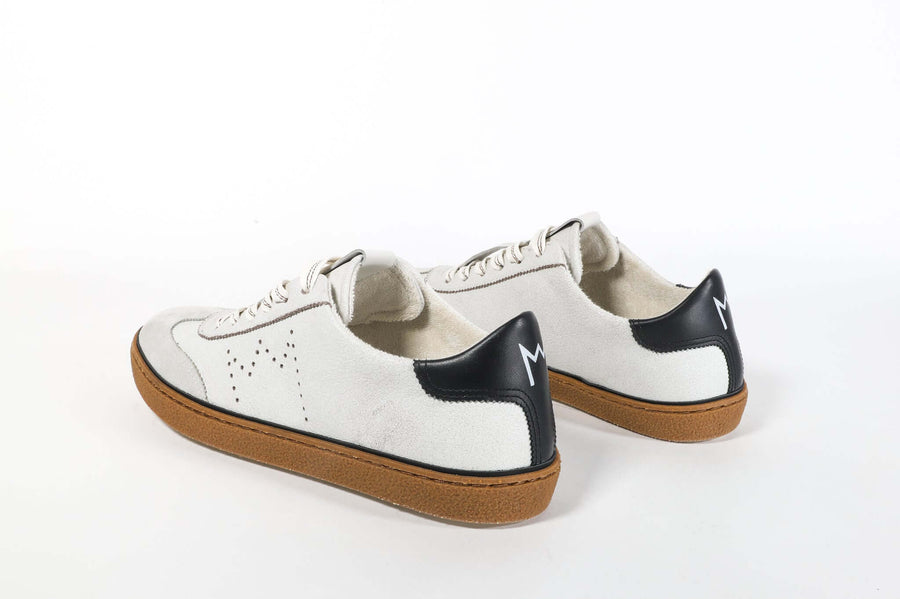 Three quarter back view of low top retro sneaker in white and grey with navy detailing and perforated crown logo on upper. Full leather upper and honey colored recycled rubber sole.