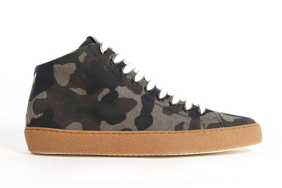 Side profile of mid top camouflage print sneaker with full canvas upper, internal zip and honey colored recycled rubber sole.