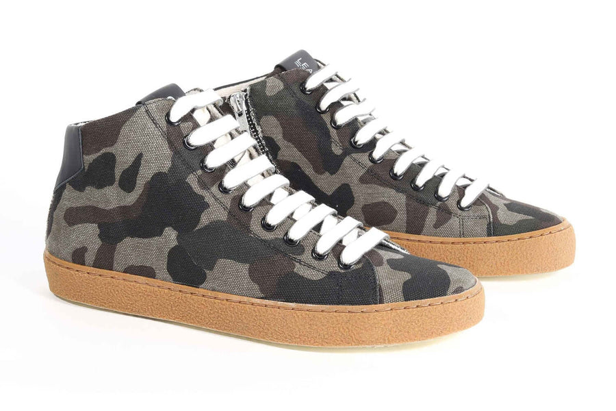 Three quarter front view of mid top camouflage print sneaker with full canvas upper, internal zip and honey colored recycled rubber sole.