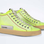Three quarter front view of high top canvas sneaker. Canvas upper hand painted in gradated fluo yellow paint. Pale natural rubber sole.