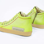 Back view of high top canvas sneaker. Canvas upper hand painted in gradated fluo yellow paint. Pale natural rubber sole.