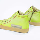 Back view of high top canvas sneaker. Canvas upper hand painted in gradated fluo yellow paint. Pale natural rubber sole.