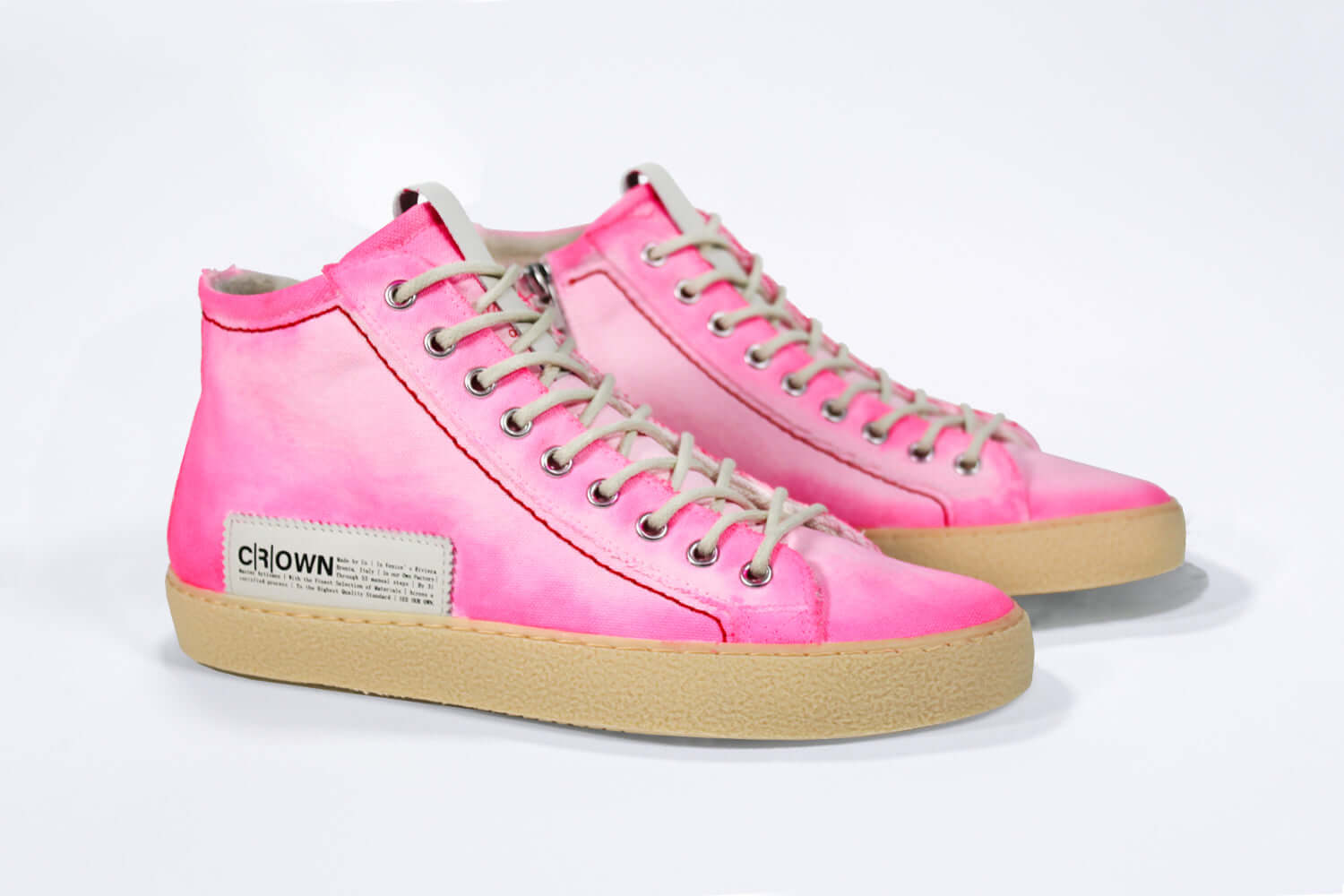 Three quarter front view of high top canvas sneaker. Canvas upper hand painted in gradated fluo pink paint. Pale natural rubber sole.