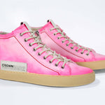 Three quarter front view of high top canvas sneaker. Canvas upper hand painted in gradated fluo pink paint. Pale natural rubber sole.