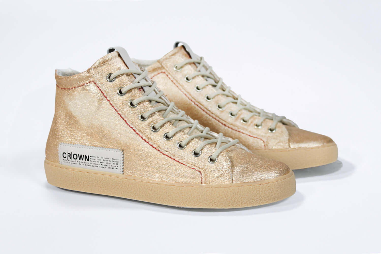 Three quarter front view of high top canvas sneaker. Canvas upper hand painted in gradated gold paint. Natural rubber sole.