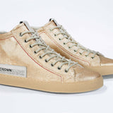 Three quarter front view of high top canvas sneaker. Canvas upper hand painted in gradated gold paint. Natural rubber sole.