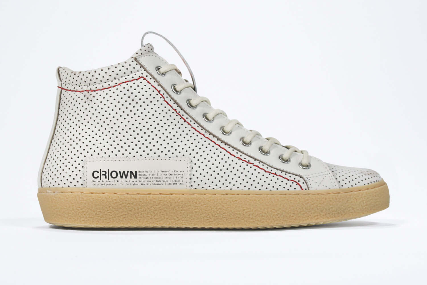 Side profile of high top sneaker. Perforated aged white leather sneakers with signature red stitching and pale natural rubber sole.