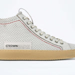 Side profile of high top sneaker. Perforated aged white leather sneakers with signature red stitching and pale natural rubber sole.