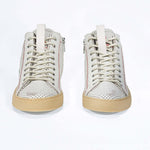 Front view of high top sneaker. Perforated aged white leather sneakers with signature red stitching and pale natural rubber sole.