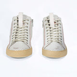 Front view of high top sneaker. Perforated aged white leather sneakers with signature red stitching and pale natural rubber sole.