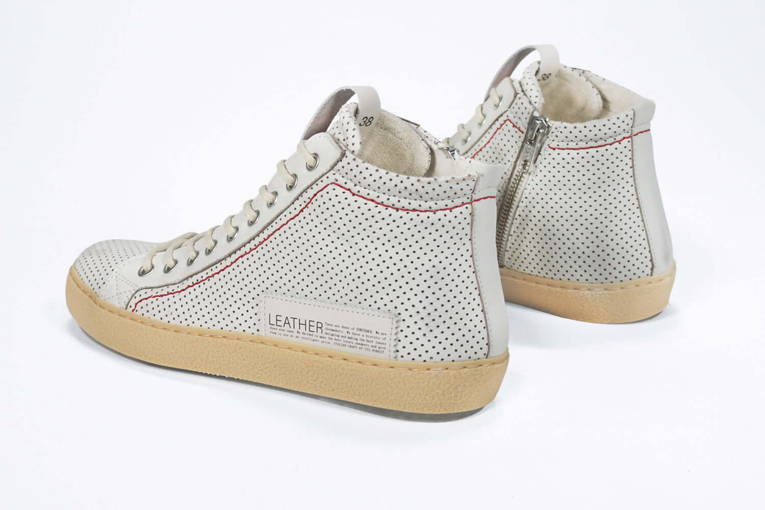 Back view of high top sneaker. Perforated aged white leather sneakers with signature red stitching and pale natural rubber sole.