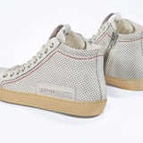Back view of high top sneaker. Perforated aged white leather sneakers with signature red stitching and pale natural rubber sole.