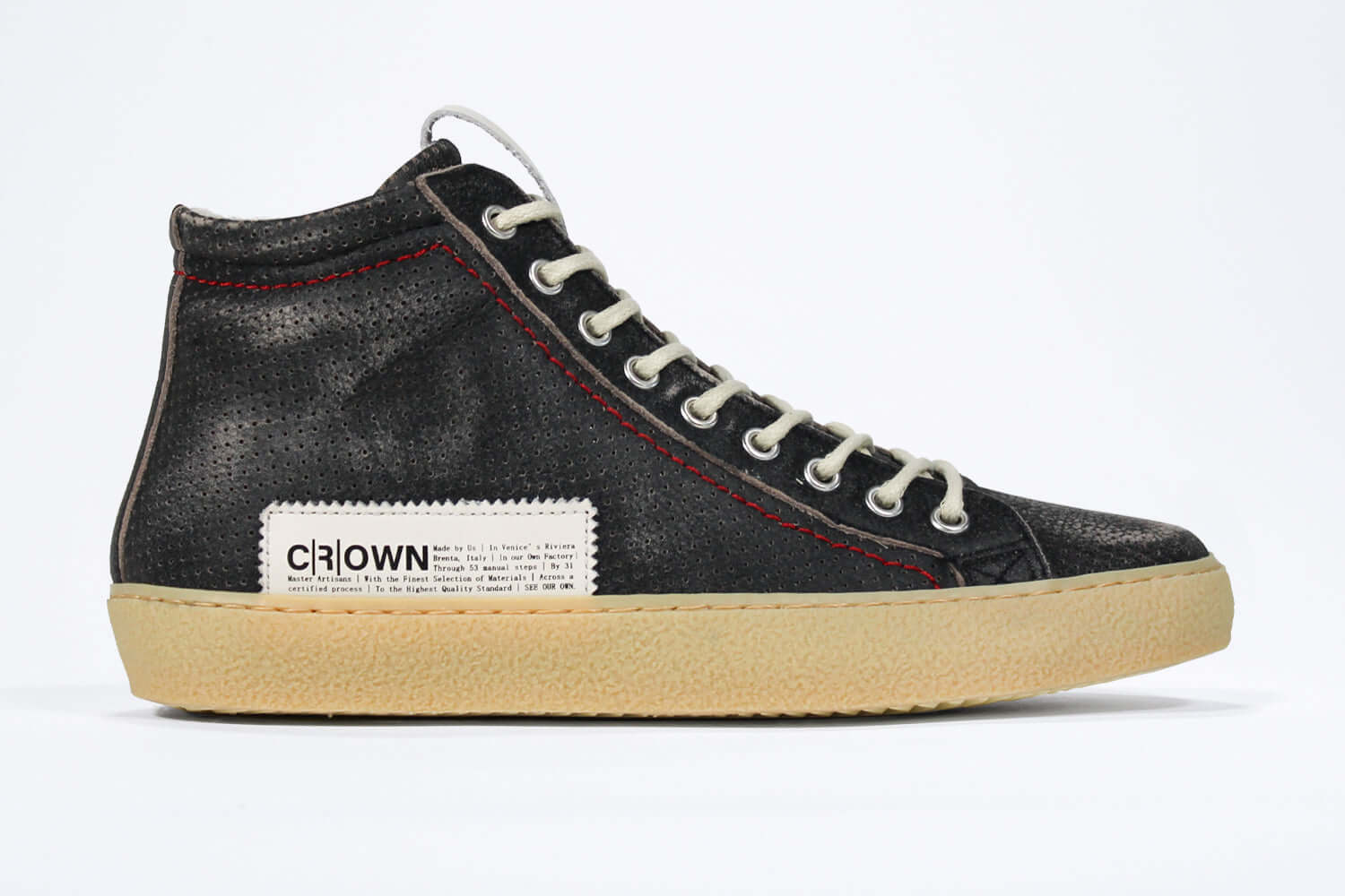 Side profile of high top sneaker. Perforated distressed black leather sneakers with signature red stitching and pale natural rubber sole.