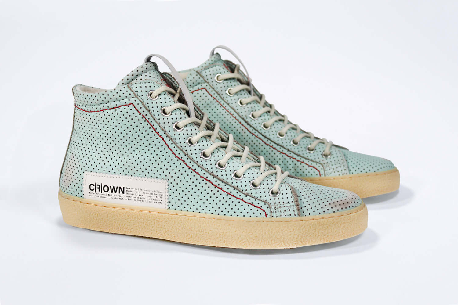 Three quarter front view of high top sneaker. Perforated sky blue leather sneakers with signature red stitching and pale natural rubber sole.