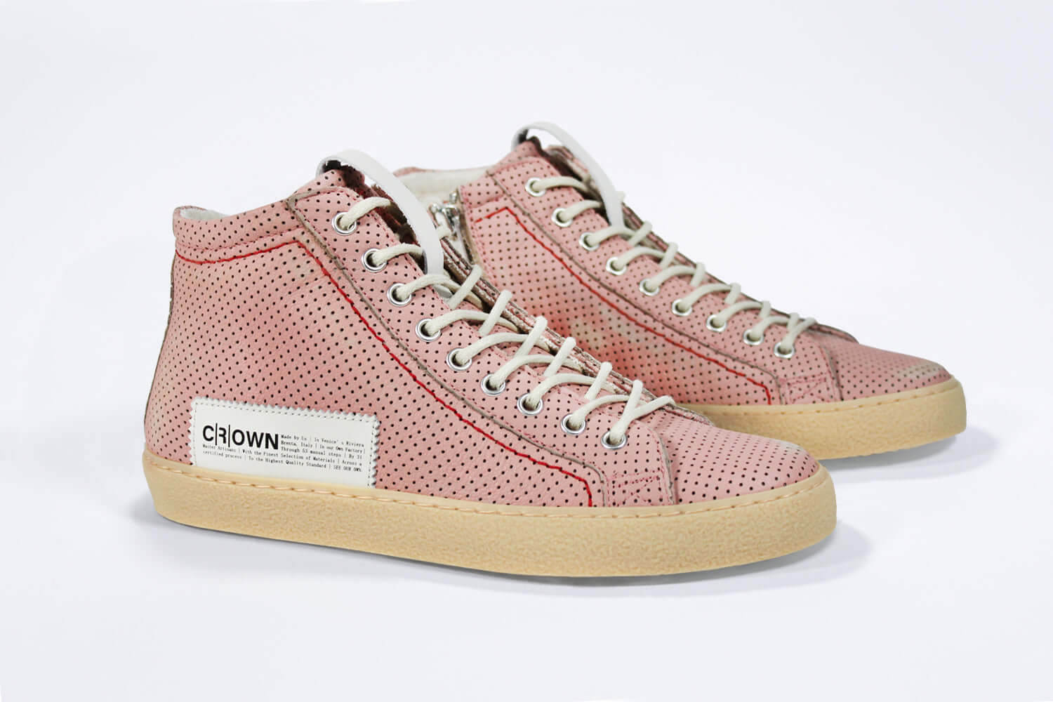 Three quarter front view of high top sneaker. Perforated pink leather sneakers with signature red stitching and pale natural rubber sole.