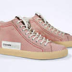 Three quarter front view of high top sneaker. Perforated pink leather sneakers with signature red stitching and pale natural rubber sole.