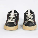 Front view of low top perforated aged black leather sneaker with red stitching detail and a pale natural rubber sole.