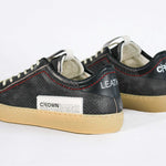 Back view of low top perforated aged black leather sneaker with red stitching detail and a pale natural rubber sole.