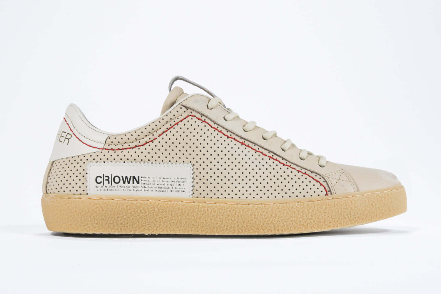 Side profile of low top sneaker. Perforated milk leather sneakers with signature red stitching and pale natural rubber sole.