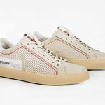 Three quarter front view of low top sneaker. Perforated milk leather sneakers with signature red stitching and pale natural rubber sole.