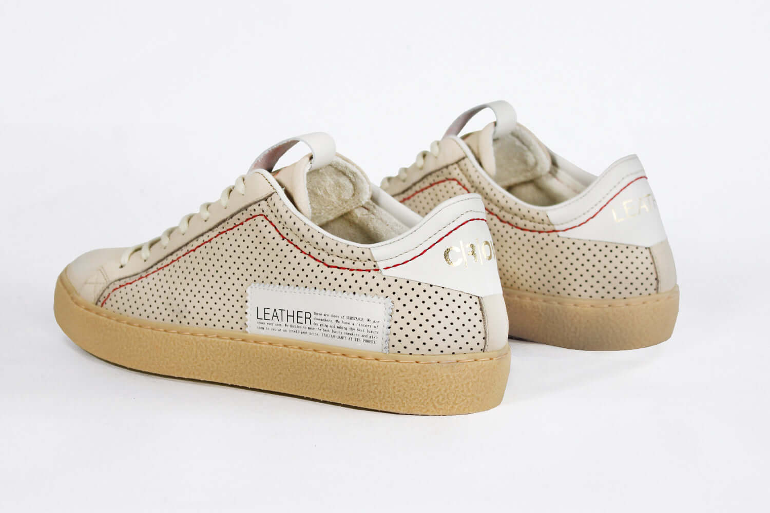 Back view of low top sneaker. Perforated milk leather sneakers with signature red stitching and pale natural rubber sole.