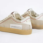 Back view of low top sneaker. Perforated milk leather sneakers with signature red stitching and pale natural rubber sole.