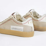 Back view of low top sneaker. Perforated milk leather sneakers with signature red stitching and pale natural rubber sole.