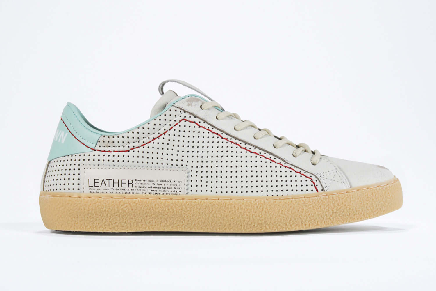 Side profile of low top perforated aged white leather sneaker with pale blue accents, red stitching detail and pale rubber sole.