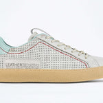 Side profile of low top perforated aged white leather sneaker with pale blue accents, red stitching detail and pale rubber sole.