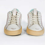 Front view of low top perforated aged white leather sneaker with pale blue accents, red stitching detail and pale rubber sole.