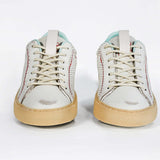 Front view of low top perforated aged white leather sneaker with pale blue accents, red stitching detail and pale rubber sole.