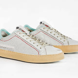 Three quarter front view of low top perforated aged white leather sneaker with pale blue accents, red stitching detail and pale rubber sole.