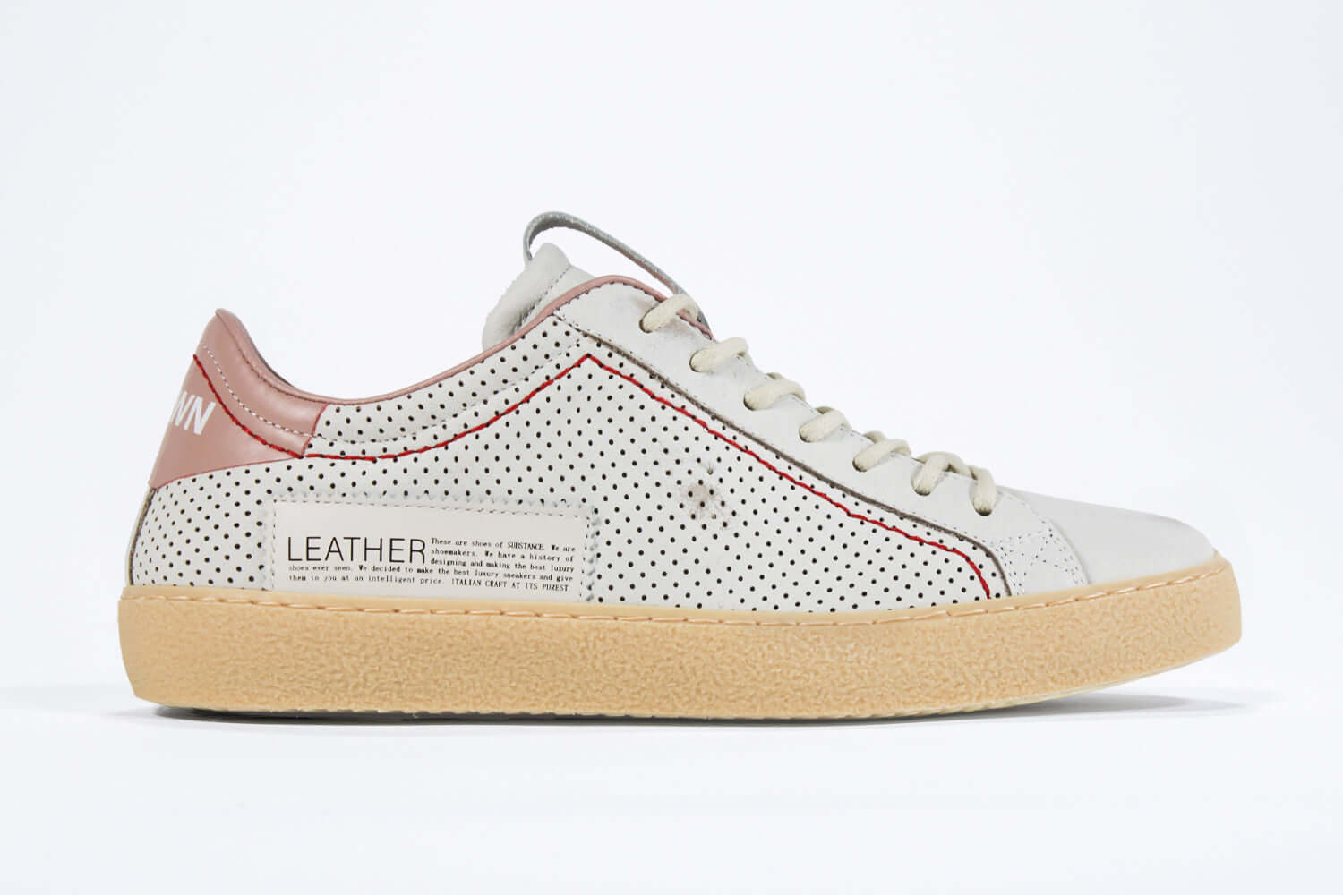 Side profile of low top perforated aged white leather sneaker with blush pink accents, red stitching detail and pale natural rubber sole.