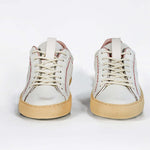 Front view of low top perforated aged white leather sneaker with blush pink accents, red stitching detail and pale natural rubber sole.