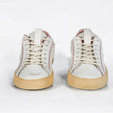 Front view of low top perforated aged white leather sneaker with blush pink accents, red stitching detail and pale natural rubber sole.