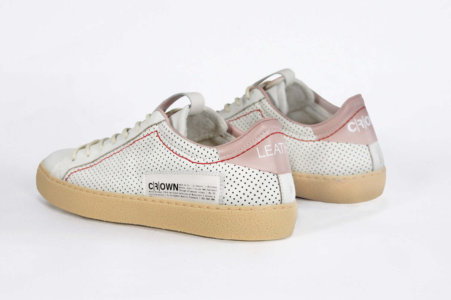 Back view of low top perforated aged white leather sneaker with blush pink accents, red stitching detail and pale natural rubber sole.