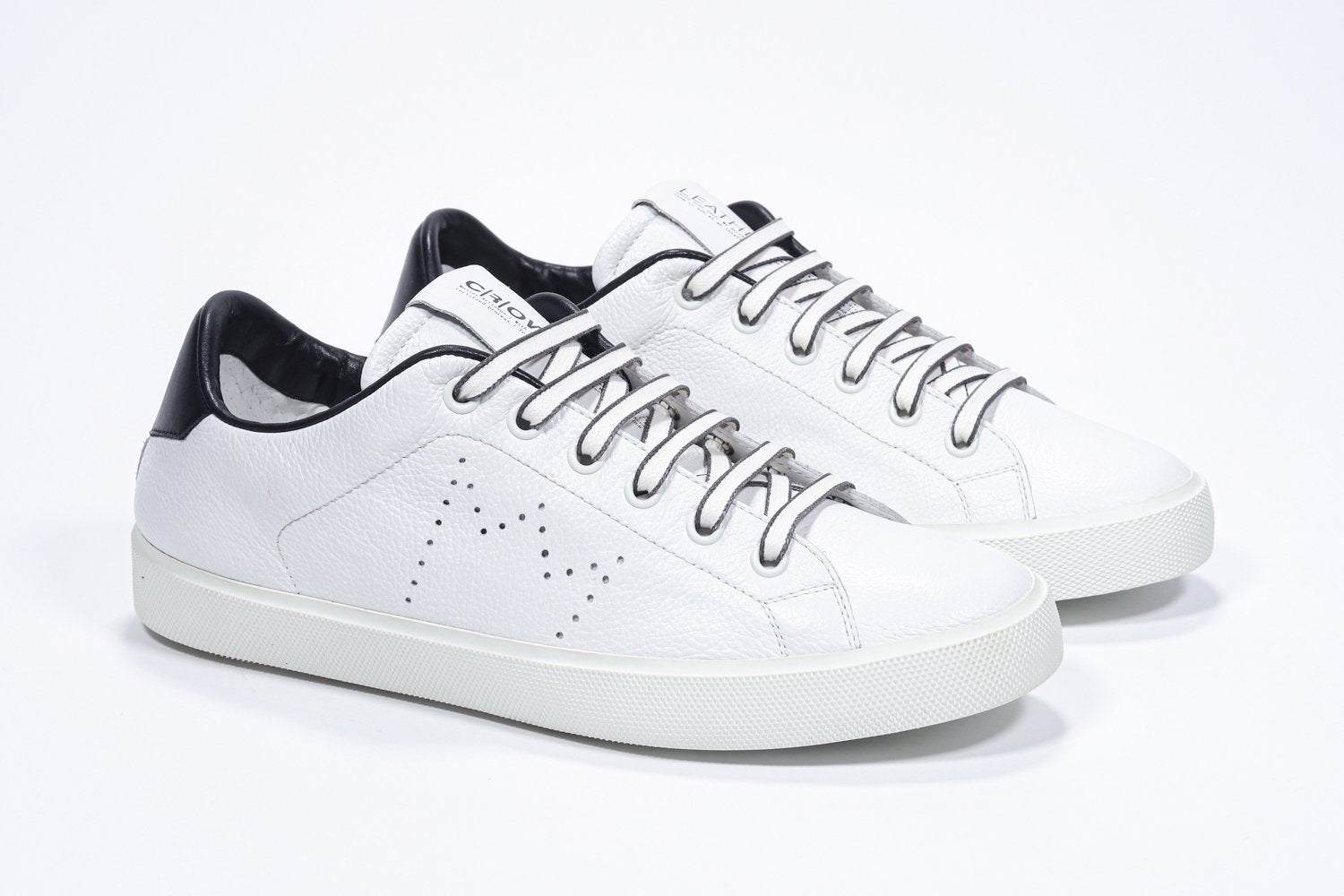 Dreiviertelansicht des weißen Low Top sneaker mit schwarzen Details und perforiertem Kronenlogo auf dem Obermaterial. Obermaterial aus Vollleder und weiße Gummisohle.