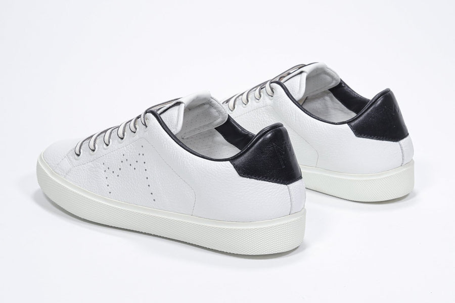 Three quarter back view of low top white sneaker with black detailing and perforated crown logo on upper. Full leather upper and white rubber sole.