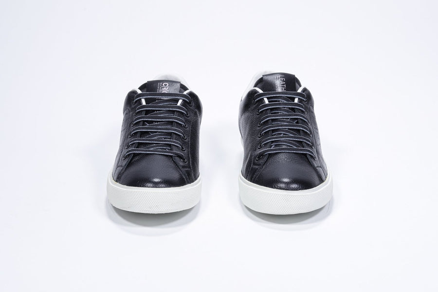 Front view of low top black sneaker with white detailing and perforated crown logo on upper. Full leather upper and white rubber sole.