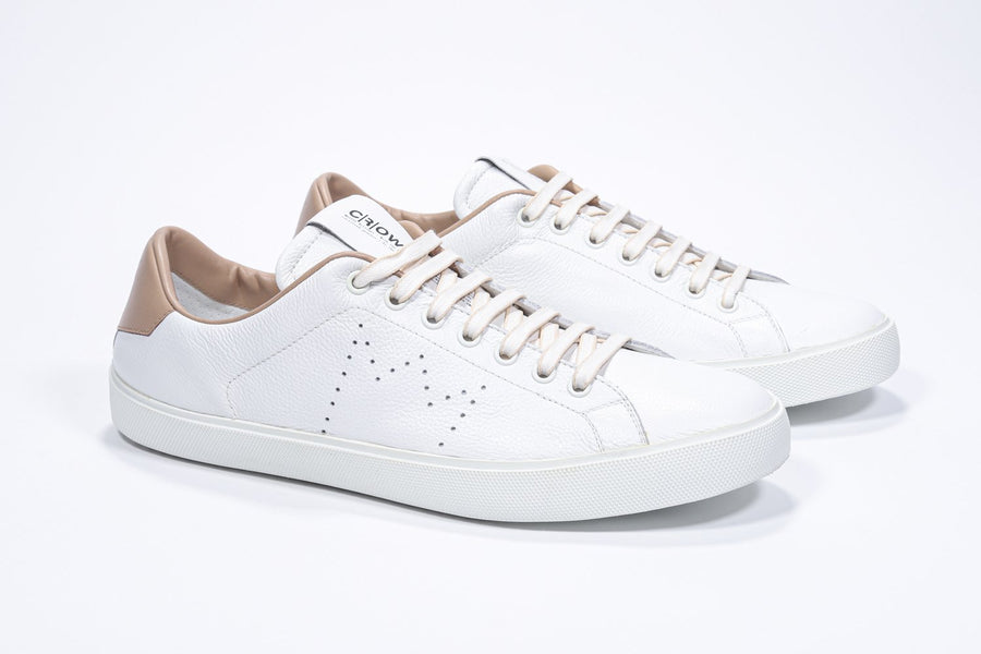 Three quarter front view of low top white sneaker with cuoio detailing and perforated crown logo on upper. Full leather upper and white rubber sole.