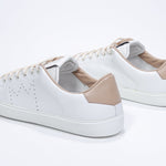 Three quarter back view of low top white sneaker with cuoio detailing and perforated crown logo on upper. Full leather upper and white rubber sole.