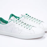 Three quarter front view of low top white sneaker with green detailing and perforated crown logo on upper. Full leather upper and white rubber sole.