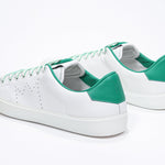 Three quarter back view of low top white sneaker with green detailing and perforated crown logo on upper. Full leather upper and white rubber sole.