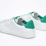 Three quarter back view of low top white sneaker with green detailing and perforated crown logo on upper. Full leather upper and white rubber sole.