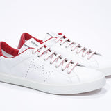 Three quarter front view of low top white sneaker with red detailing and perforated crown logo on upper. Full leather upper and white rubber sole.