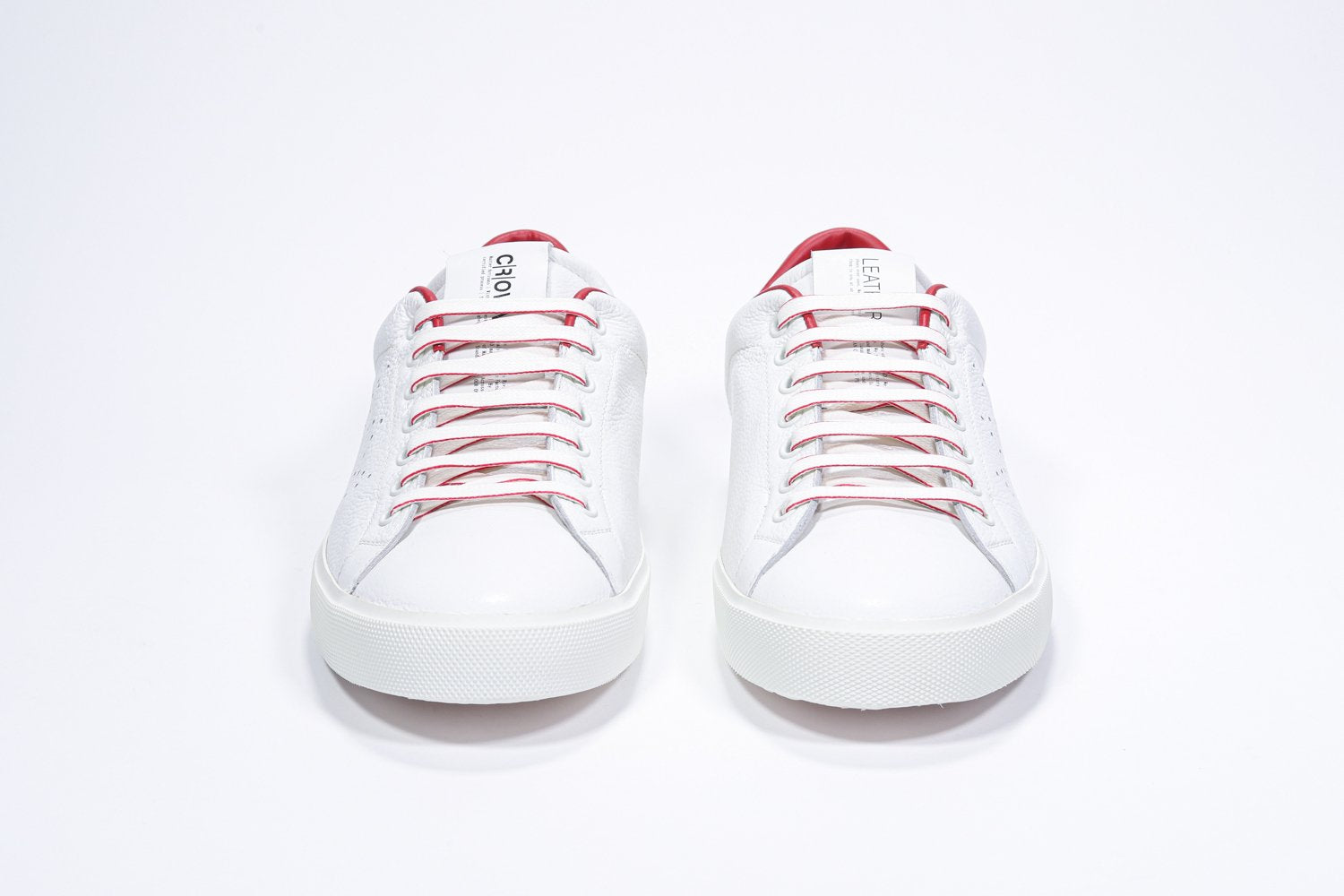 Front view of low top white sneaker with red detailing and perforated crown logo on upper. Full leather upper and white rubber sole.