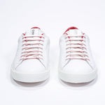 Front view of low top white sneaker with red detailing and perforated crown logo on upper. Full leather upper and white rubber sole.