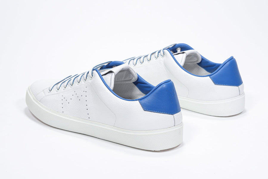 Three quarter back view of low top white sneaker with blue detailing and perforated crown logo on upper. Full leather upper and white rubber sole.