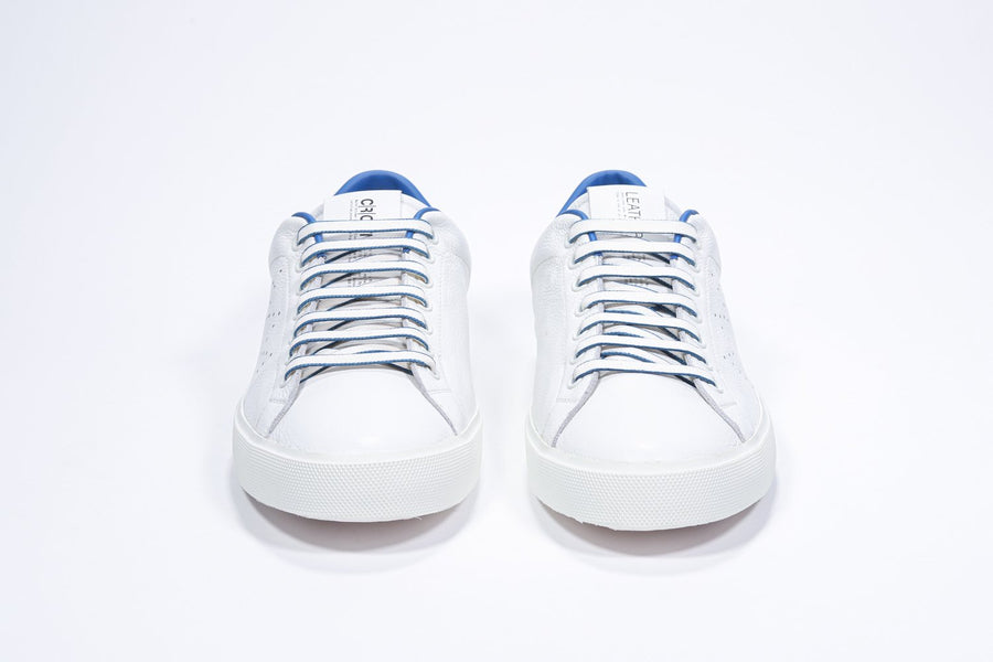 Front view of low top white sneaker with blue detailing and perforated crown logo on upper. Full leather upper and white rubber sole.